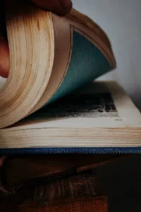 a person is holding an open book with a blue cover