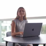 a woman sitting at a table with a laptop